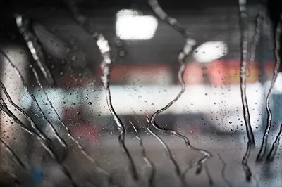 عکس نمایی از شستشوی خودرو با آب بر روی شیشه جلو از داخل ماشین