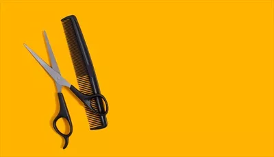 عکس تصویری از ابزار آرایشگری شامل قیچی و شانه بر روی زمینه زرد