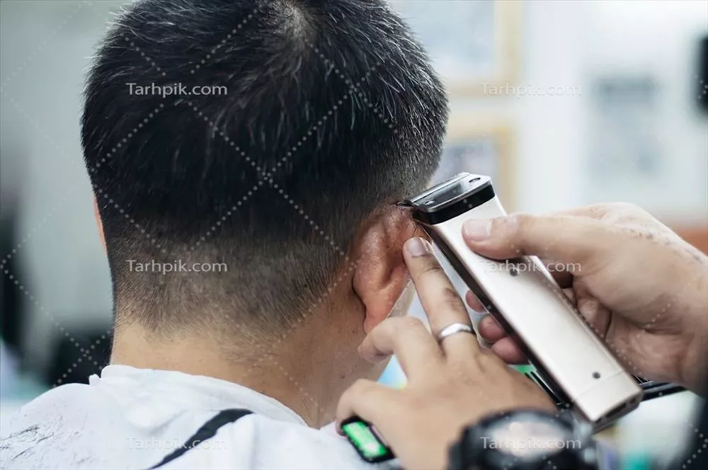 عکس مردی که در آرایشگاه مشغول کوتاه کردن موهایش است و افراد دیگر در حال تماشا هستند