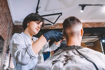 عکس آرایشگر حرفه ای در حال اصلاح موهای مشتری با ماشین اصلاح برقی