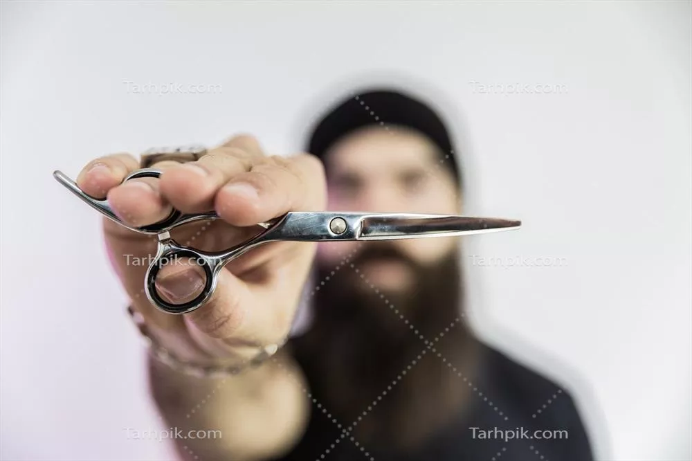 عکس آرایشگر با ریش بلند در حال استفاده از قیچی برای اصلاح موها