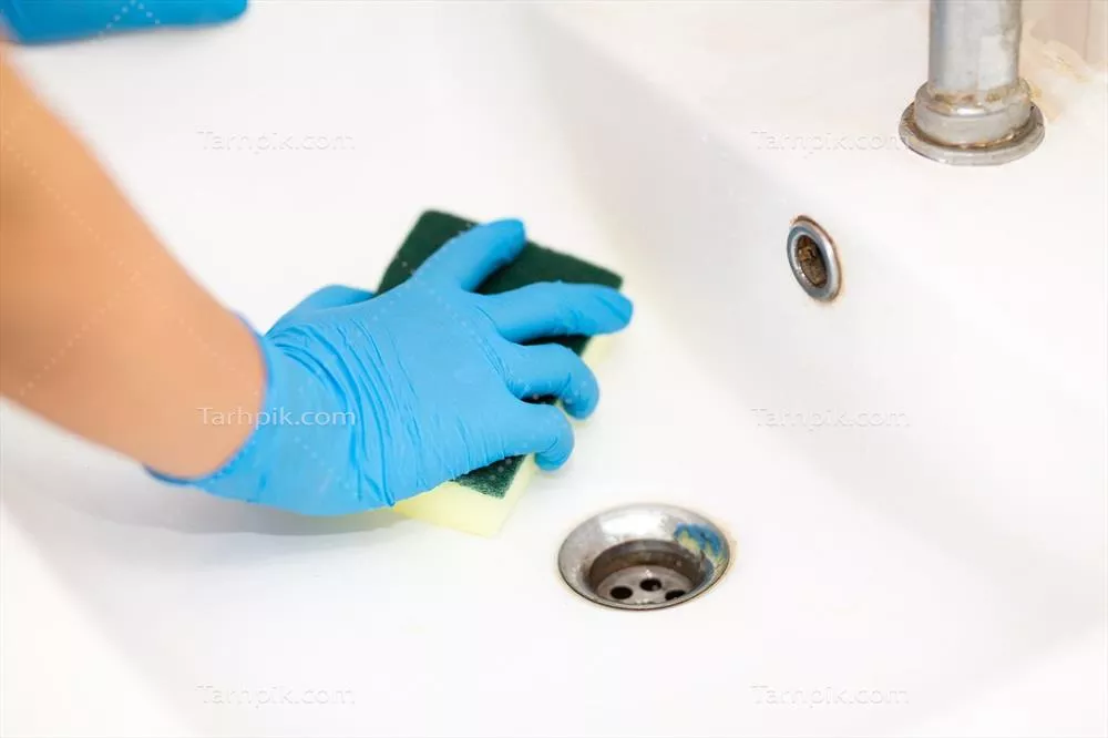 عکس شخصی با دستکش لاستیکی آبی در حال تمیز کردن سینک حمام