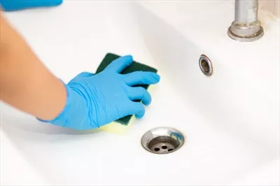 عکس شخصی با دستکش لاستیکی آبی در حال تمیز کردن سینک حمام