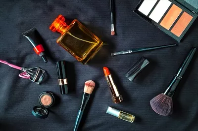 عکس محصولات آرایشی و عطر در کنار هم بر روی پارچه مشکی