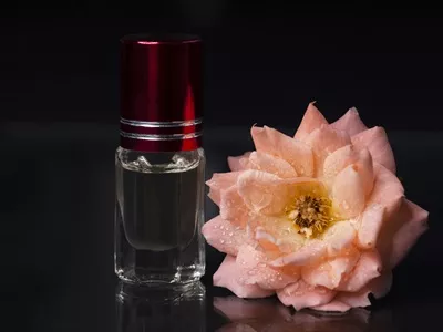 عکس عطر متمرکز در بطری کوچک با رایحه گل سرخ صورتی بر روی پس زمینه سیاه