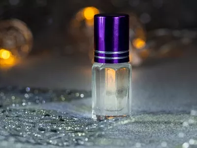 عکس عطر متمرکز در بطری مینیاتوری با رایحه مشک بر روی پس زمینه مشکی جشنواره ای