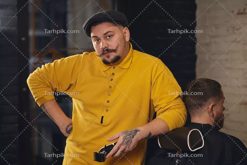 عکس آرایشگری که موهای مردی با ریش جذاب را در آرایشگاه کوتاه می کند
