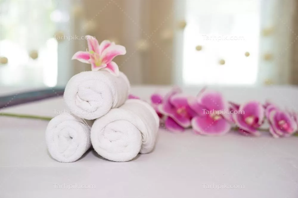 عکس گل ارکیده صورتی زیبا بر روی حوله سفید در سالن اسپا