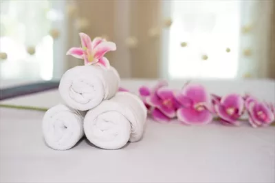 عکس گل ارکیده صورتی زیبا بر روی حوله سفید در سالن اسپا