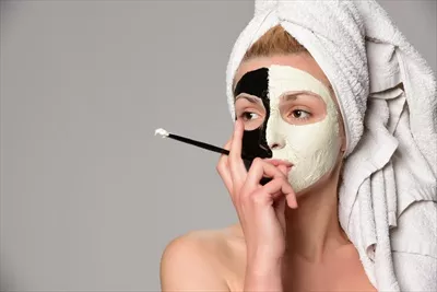 عکس مدل زن زیبا با ماسک صورت سیاه و سفید در حال گاز زدن پرتقال برش خورده