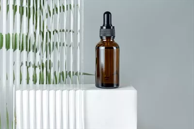 روغن صورت زیبایی در بطری شیشه ای کهربایی: عکسی از بسته بندی مدرن و طبیعی