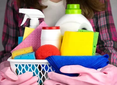 عکس زنی با دستکش لاستیکی در حال نگهداری مواد شوینده برای نظافت منزل