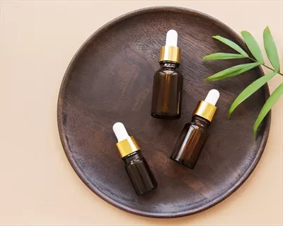 عکس تصویری زیبا از یک صفحه چوبی با بطری های روغن های معطر