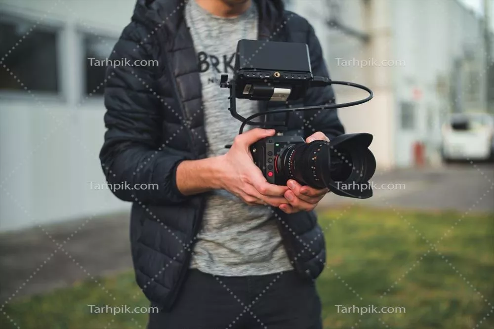 عکس شخصی در حال ضبط ویدیو با دوربین در یک محیط طبیعی