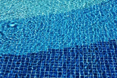 عکس موزاییک کف استخر با الگوهای موجی و تابش نور در تابستان