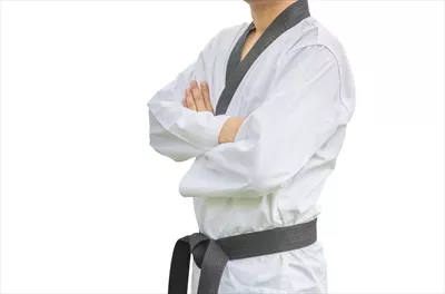 عکس تصویری از یک جوان با کمربند سیاه تکواندو در حال تمرین و ژست گرفتن