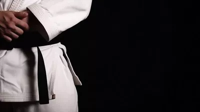 عکس مردی در لباس کاراته با کمربند سیاه، نماد تسلط و مهارت در هنرهای رزمی