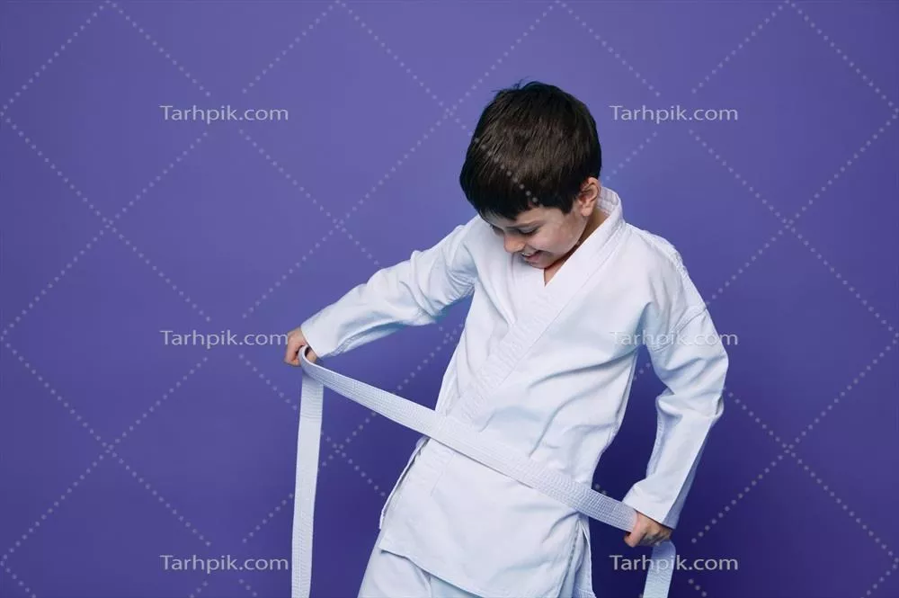 عکس پسر بچه ای شاد و با اعتماد به نفس در حال بستن کمربند کیک بوکسینگ خود