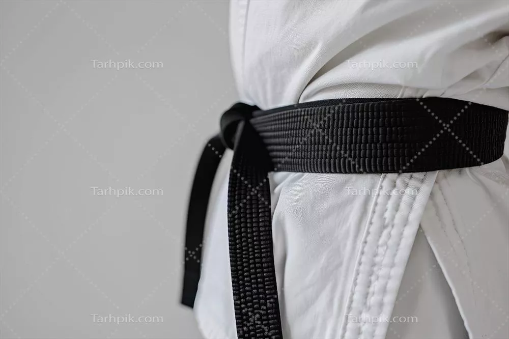 عکس تصویری از یک کاراته کار با کمربند سیاه در لباس سفید