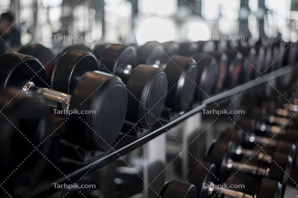 عکس تصویری از ردیف دمبل ها در یک باشگاه ورزشی برای تمرینات قدرتی