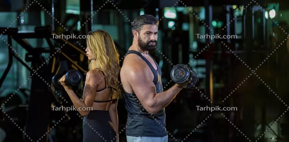عکس تصویری از یک زوج ورزشی با عضلات قوی در حال تمرین با دمبل در باشگاه