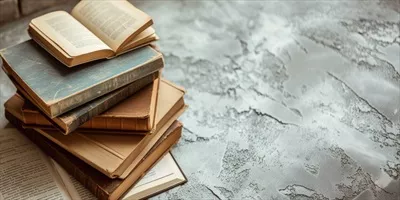 عکس تصویری زیبا از مجموعه ای از کتاب های قدیمی بر روی زمینه ای خاکستری