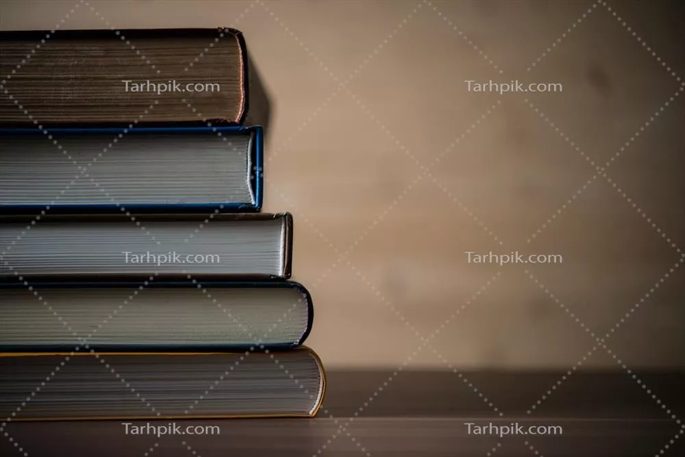 عکس مجموعه ای از کتاب ها بر روی یک میز چوبی زیبا و دلنشین