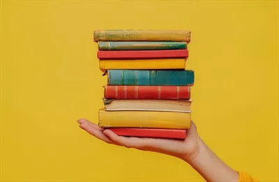 عکس دست انسان در حال نگه داشتن یک دسته کتاب های متنوع و جذاب