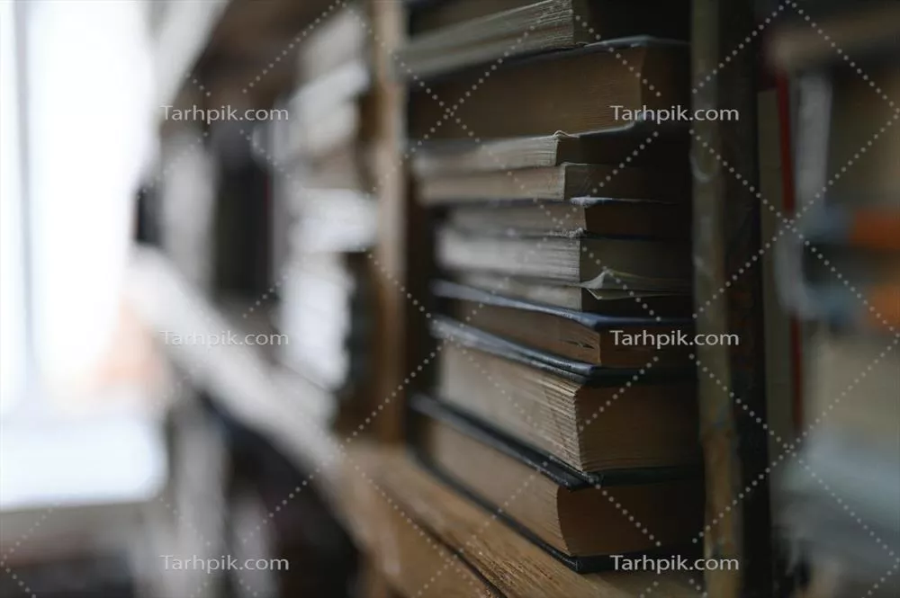 عکس پس زمینه ای محو از قفسه ای پر از کتاب های رنگارنگ و متنوع