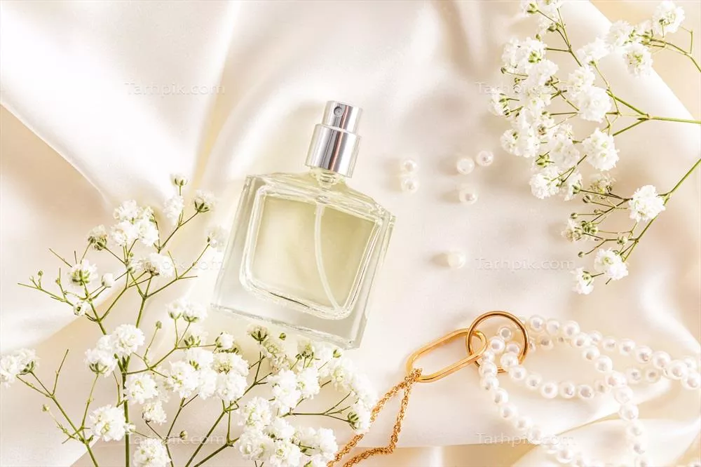 عکس نمایی زیبا از بطری عطر زنانه بر روی پارچه ساتن با پس زمینه ملایم