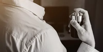 عکس مردی با ظاهری شیک و جذاب در حال استفاده از عطر با رایحه دلپذیر