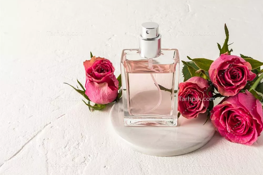 عکس بطری شیک عطر با طراحی خاص بر روی پایه مرمری و گل های چای