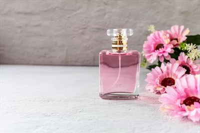 عکس بطری عطر صورتی زیبا با گل های صورتی در پس زمینه