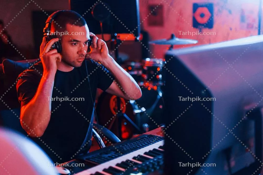 عکس مهندس صدا در حال کار و میکس موسیقی در استودیو با هدفون