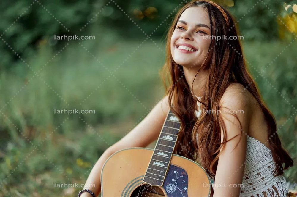 عکس زنی هیپی با لبخند و گیتار در دل طبیعت در نور غروب