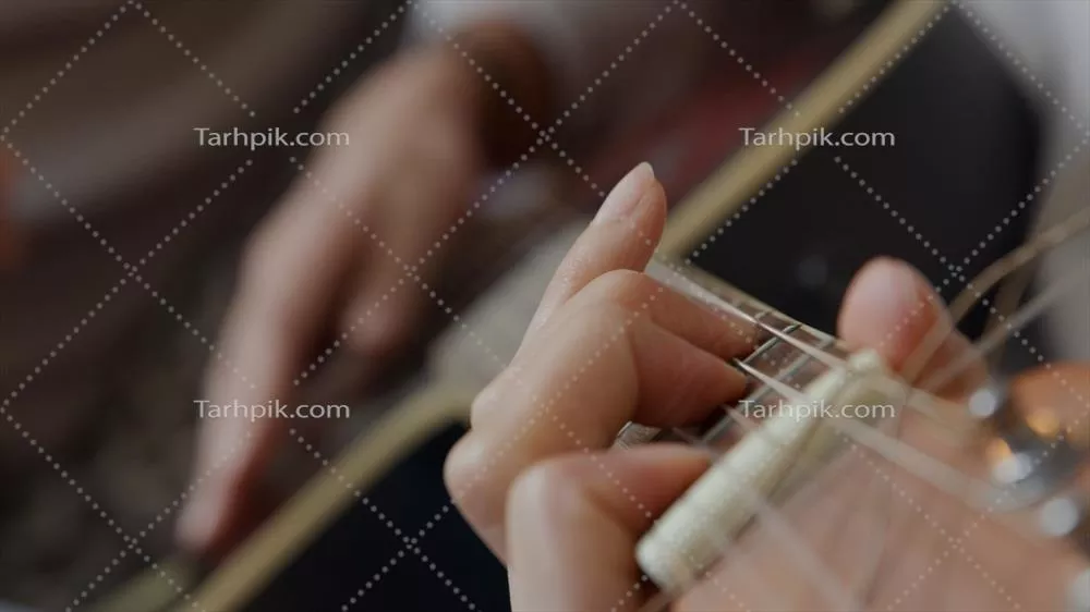 عکس نزدیک نمایی از دست یک زن جوان با نژاد مختلط که در حال تنظیم کوک های گیتار است