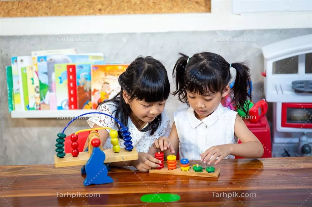 عکس دختر بچه ای که با اسباب بازی های چوبی خود در حال بازی است