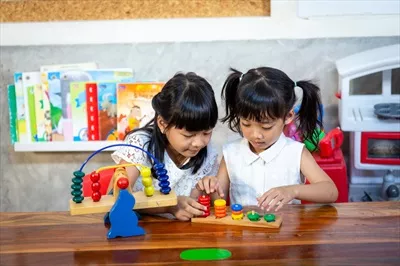 عکس دختر بچه ای که با اسباب بازی های چوبی خود در حال بازی است