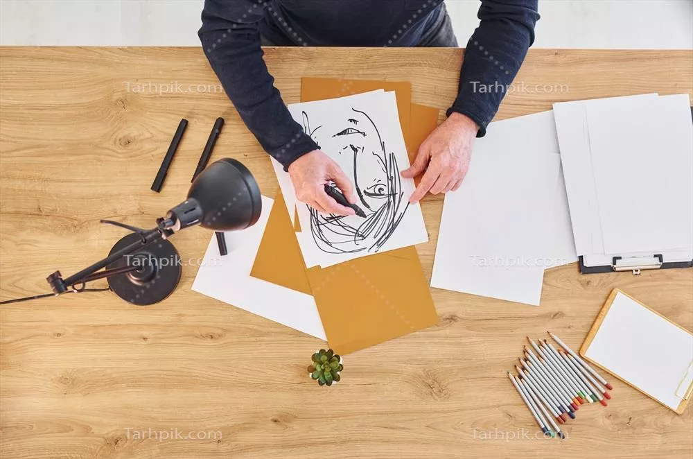 عکس نمایی از هنرمند در حال کار بر روی طرحی از یک مرد
