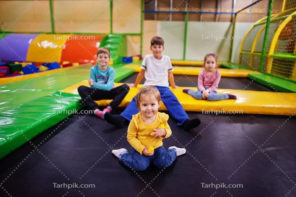 عکس کودکان در حال بازی در مرکز بازی سرپوشیده و نشسته بر روی ترامپولین