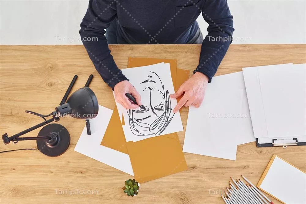 عکس نمایی از هنرمند در حال کار بر روی طرحی از یک مرد