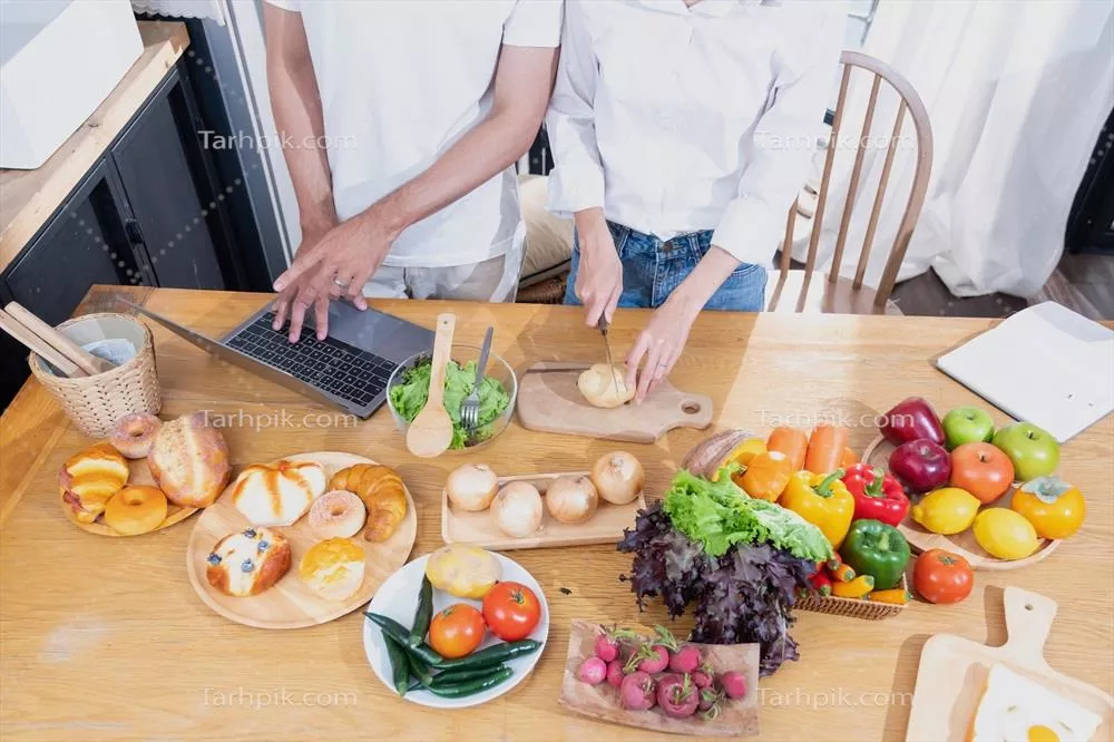 عکس زوج جوان آسیایی در حال آشپزی با میوه ها و سبزیجات در کنار هم