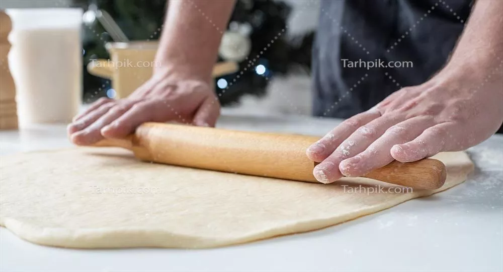 عکس سرآشپز مرد در حال کار با خمیر و تهیه رول دارچینی خوشمزه