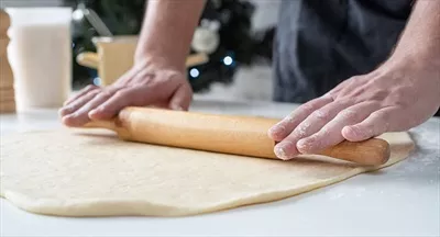 عکس سرآشپز مرد در حال کار با خمیر و تهیه رول دارچینی خوشمزه