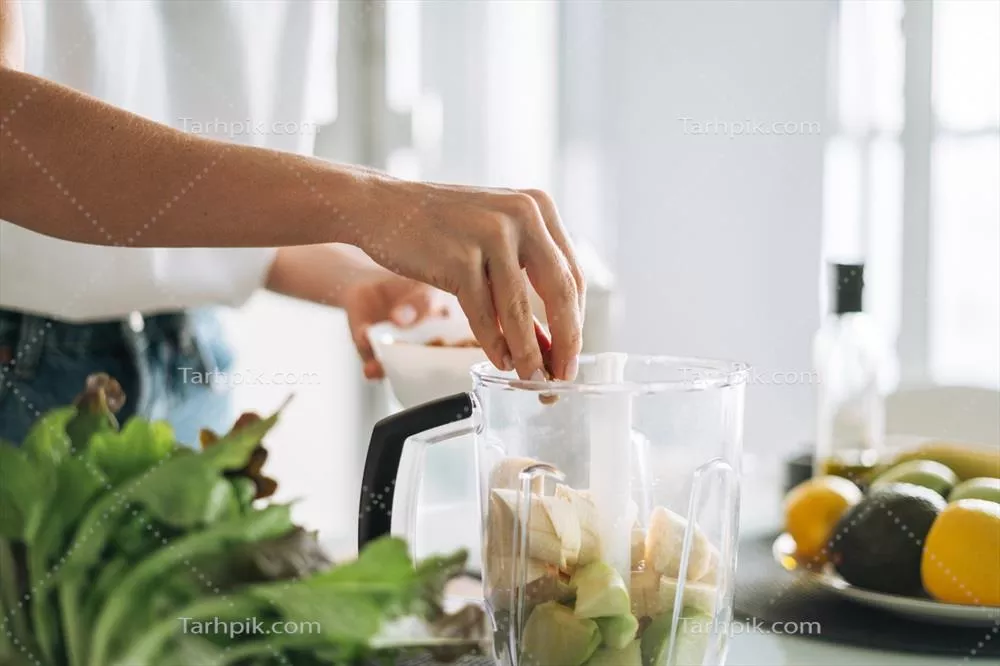 عکس زنی جوان و لاغر در حال تهیه اسموتی سالم در آشپزخانه منزل