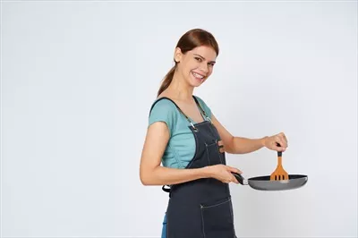 عکس زنی جوان در حال آشپزی با پیشبند در آشپزخانه، آماده برای پخت و پز