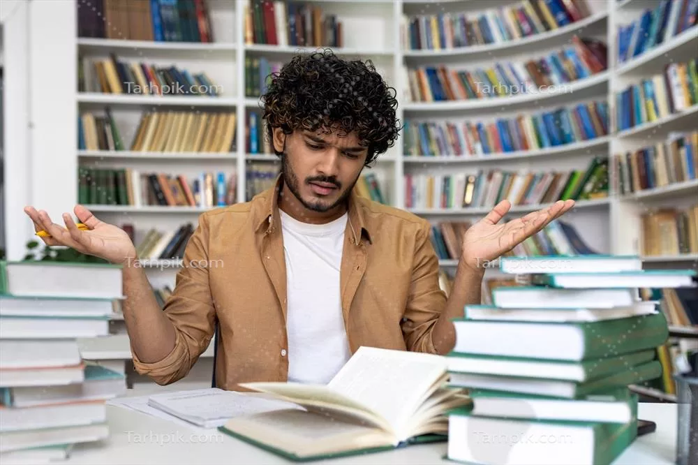 عکس دانشجویی ناامید و خسته که در تلاش است تا برای امتحان آماده شود
