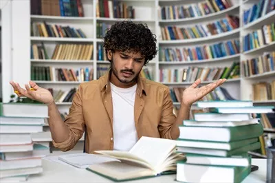 عکس دانشجویی ناامید و خسته که در تلاش است تا برای امتحان آماده شود