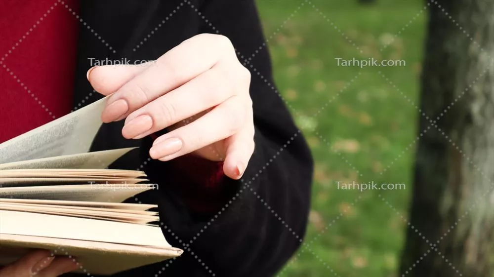 عکس دختری در پارک در حال مطالعه کتابی با دقت و آرامش