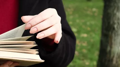 عکس دختری در پارک در حال مطالعه کتابی با دقت و آرامش